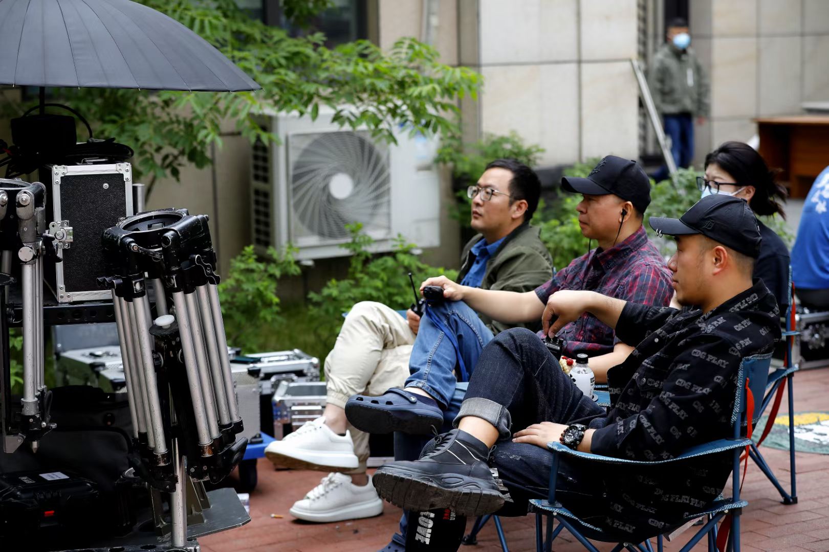 Behind the scenes on the set of Against the Wind, with a seated crew member beside professional camera equipment